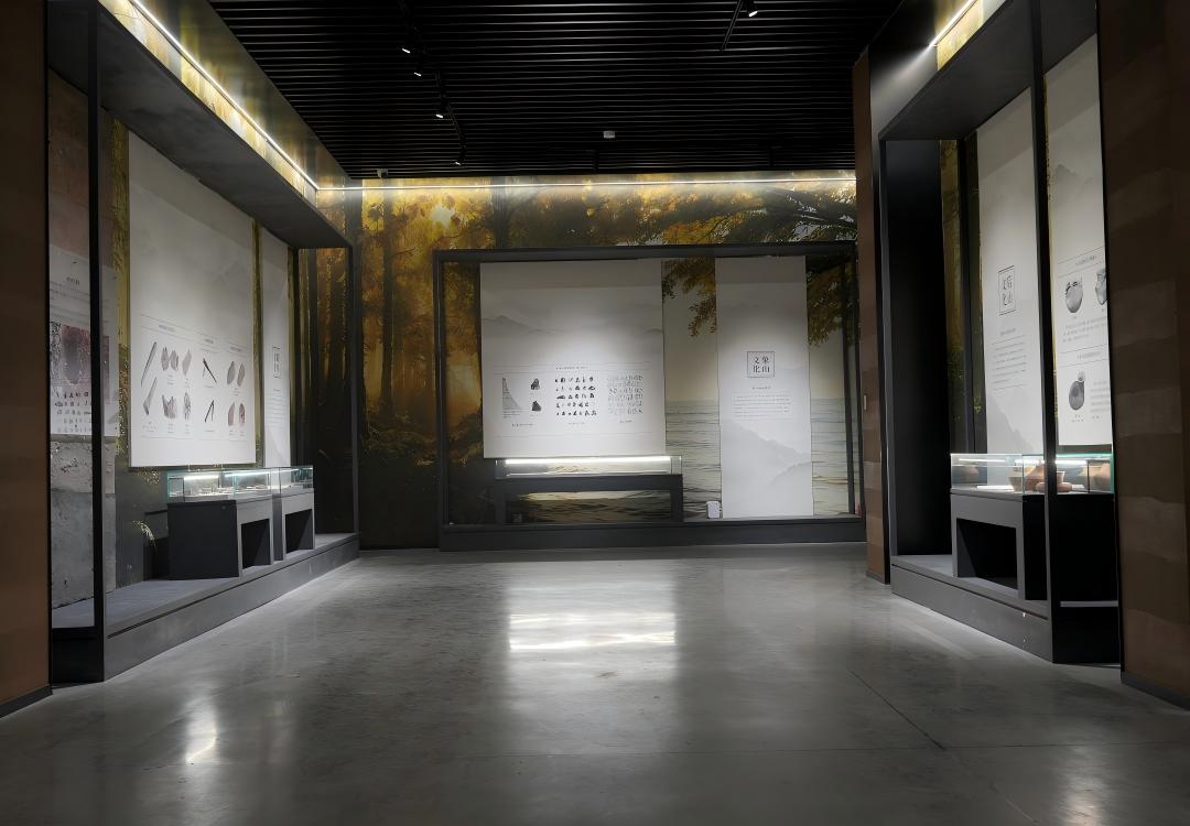 Long museum gallery with multiple small custom glass artifact display cabinets and backdrop murals