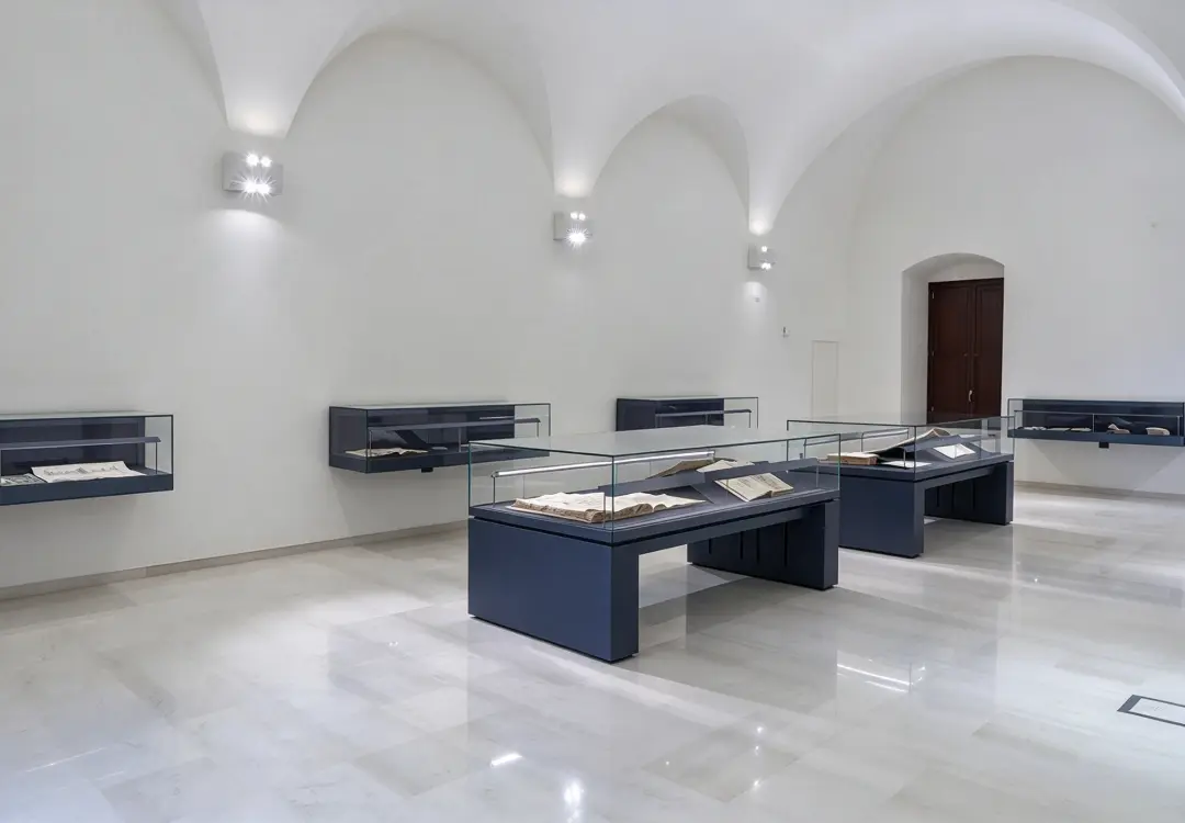 Minimalist exhibition room with low profile glass cases for displaying ancient manuscripts and documents
