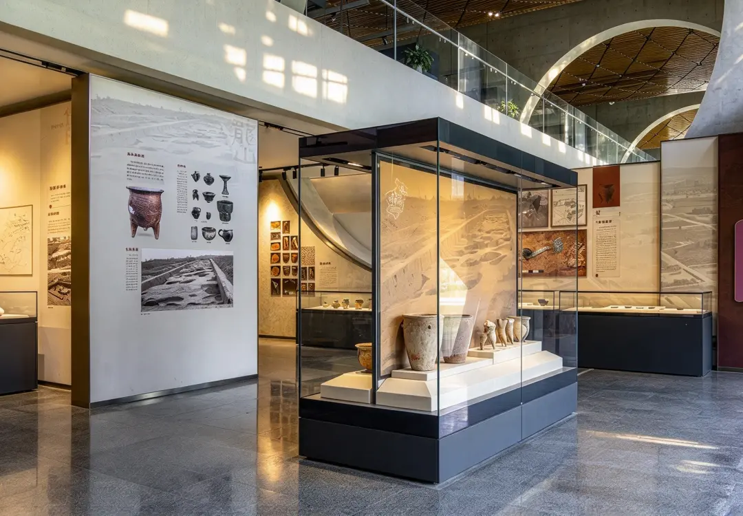 Ancient pottery artifacts showcased inside a sleek museum projection display case with graphic backdrop